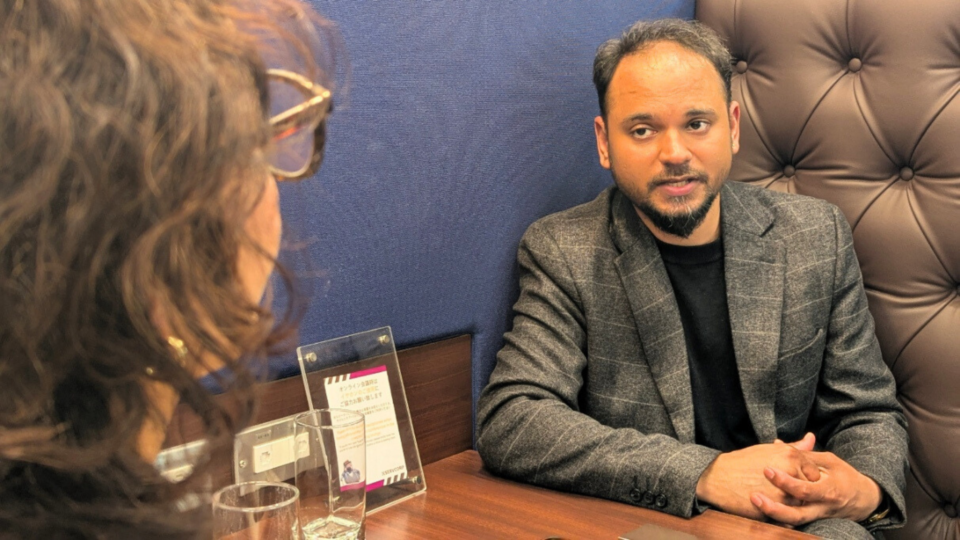 カフェのボックス席で、相手の話を聞きながら真剣に語るスーツ姿の人材コンサル