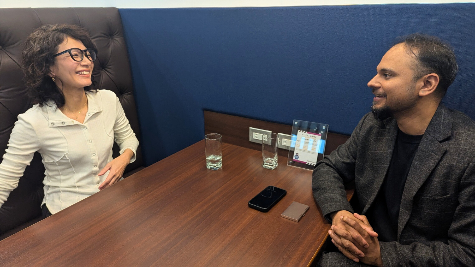 個室ブースのテーブル席で、笑顔でリラックスして談笑する二人